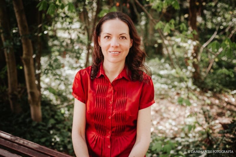 Retrato de Laura, coautora de Carolina Purpurina, con camisa roja en el jardín.