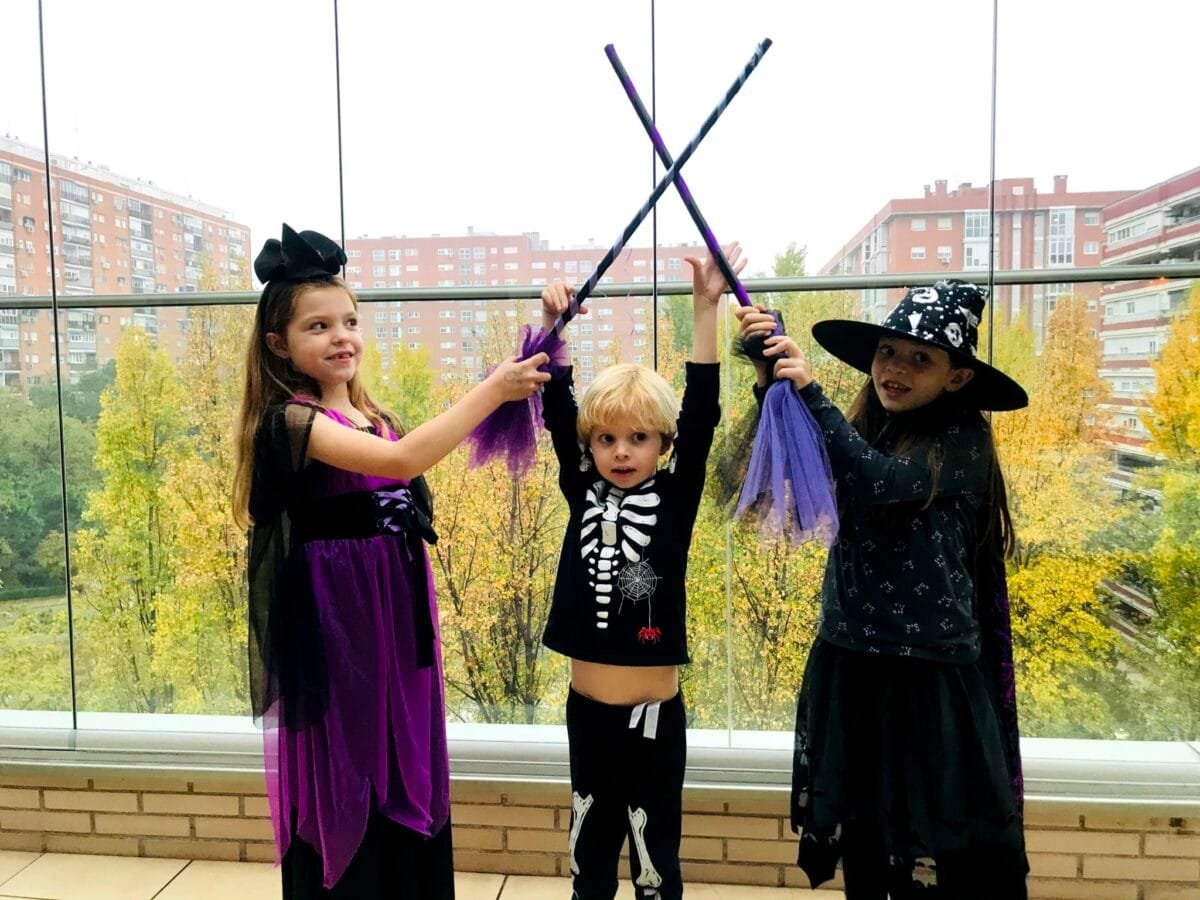 Juegos con las escobas en el cumpleaños de Carolina Purpurina: tres niños disfrazados cruzan sus escobas de bruja.