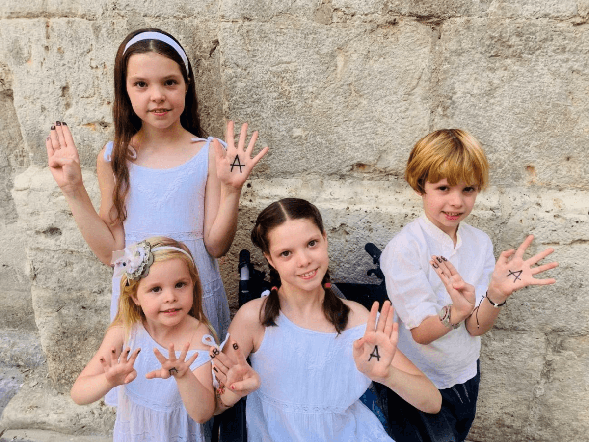 Carolina y sus hermanos posan con las letras de la Fundación Tubb4a pintadas en las manos para el calendario 2024.